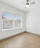 A room with a window covered by white blinds and a ceiling fan.