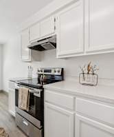 A kitchen with white cabinets and a black stove top.