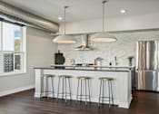 Thumbnail 3 of 4 - A kitchen with a white counter and stools.