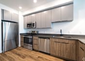 Thumbnail 4 of 8 - A modern kitchen with wooden cabinets and stainless steel appliances.