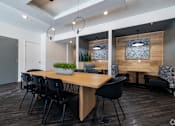 Thumbnail 7 of 8 - A modern dining room with a wooden table and black chairs.