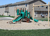 Thumbnail 8 of 9 - A playground with a green slide and a wooden structure.