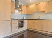 Thumbnail 6 of 7 - a large kitchen with wooden cabinets and a black tiled floor