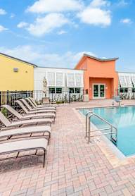 a swimming pool with chairs and buildings in the background