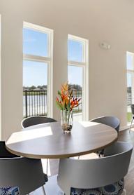 A dining room with a table surrounded by chairs and a vase of flowers on the table.