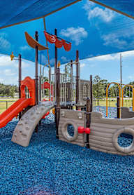 A playground with a pirate ship slide and a red slide.
