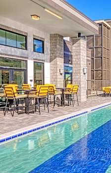 a swimming pool with tables and chairs next to a building