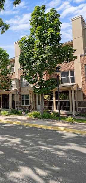 A tree-lined street in front of a brick apartment building.