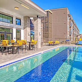 a swimming pool with tables and chairs next to a building