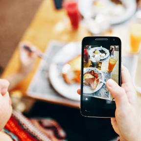 a woman taking a picture of a meal on her cell phone