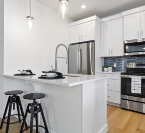 a kitchen with white cabinets and a white island with two black stools at Alante Homes at Lake Hazel, Boise, ID, 83709