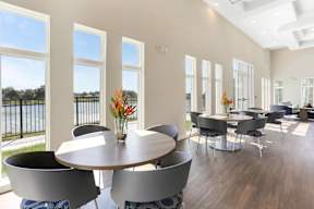 A dining room with a table surrounded by chairs and a vase of flowers on the table.