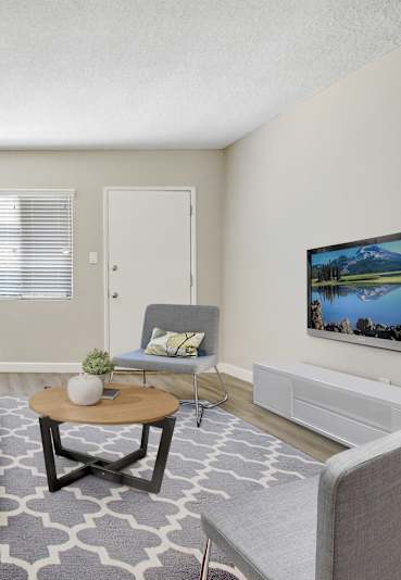 A living room with a blue couch and a television on the wall.