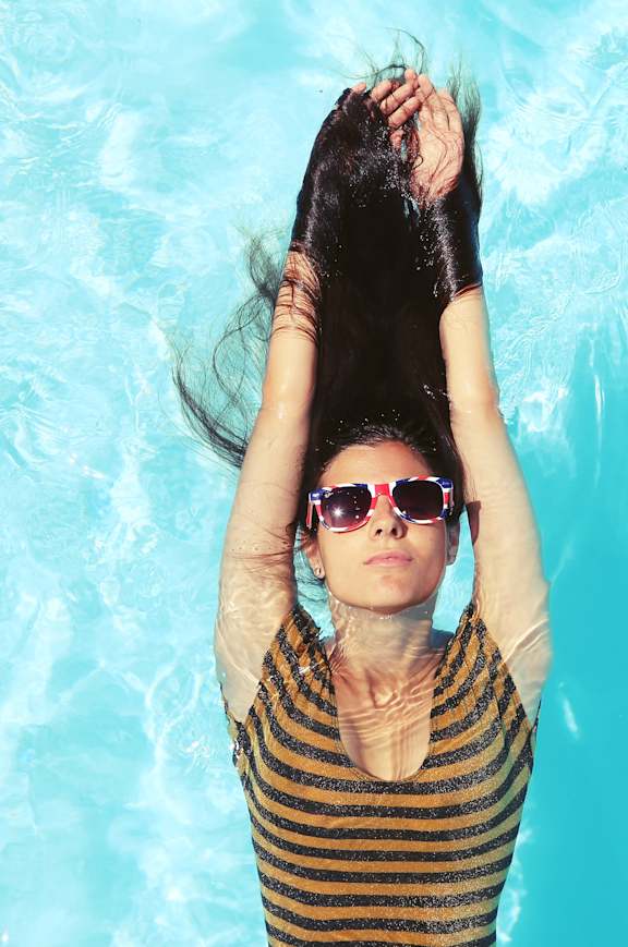 a woman laying in a pool with her hair in the water