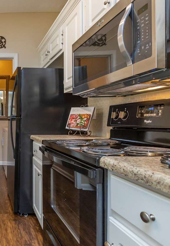 A kitchen with black appliances and white cabinets.