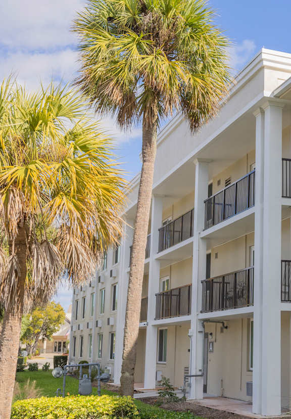 A white apartment building with balconies and air conditioning units.