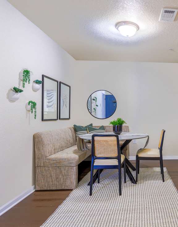 A dining room with a table set for two and a sofa.