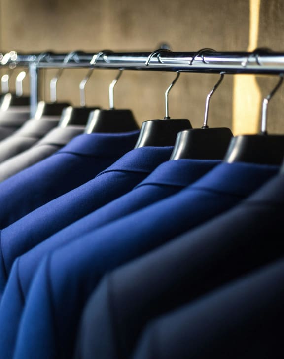 a row of shirts hanging on a rack in a closet