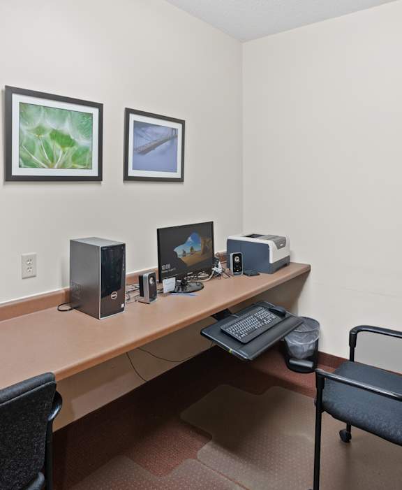 A room with a desk, two chairs, and a computer setup.