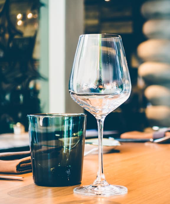 A table set for a meal with wine glasses and a glass of wine.