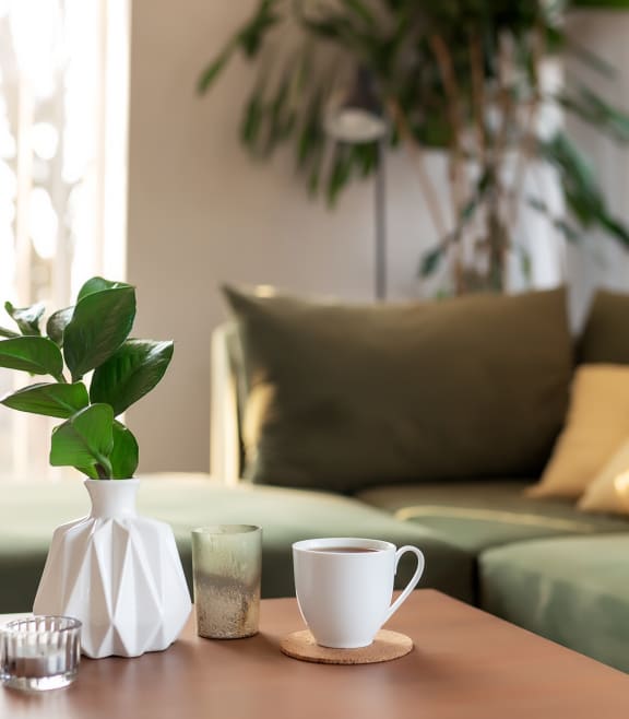 a living room with a green sofa and a coffee table with a white vase with a at Stonelake at the Arboretum, Austin, TX