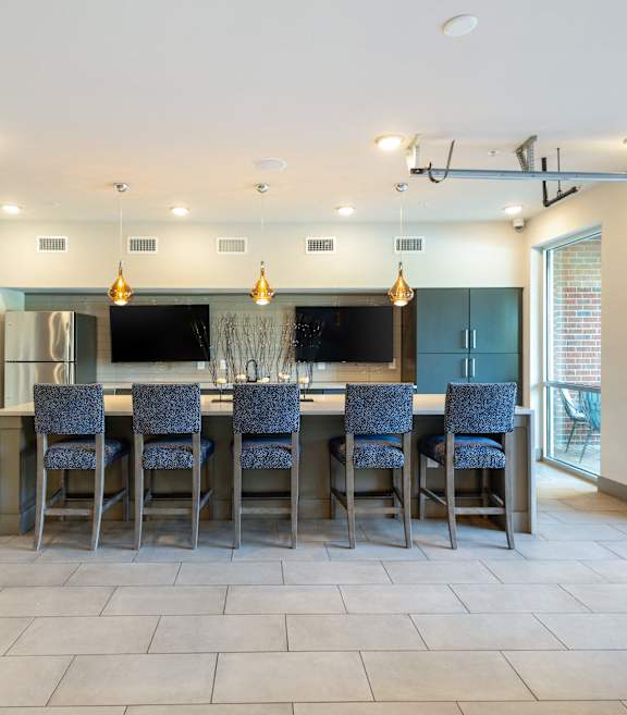 a large kitchen with a large island with blue chairs and a bar with chairs