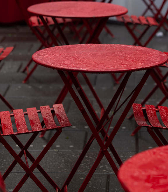 a group of red tables and chairs in the rain
