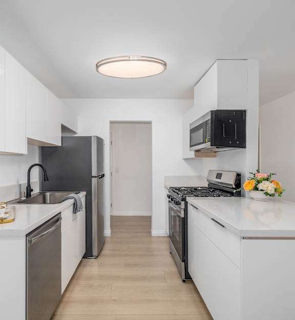 A kitchen with white cabinets and appliances.