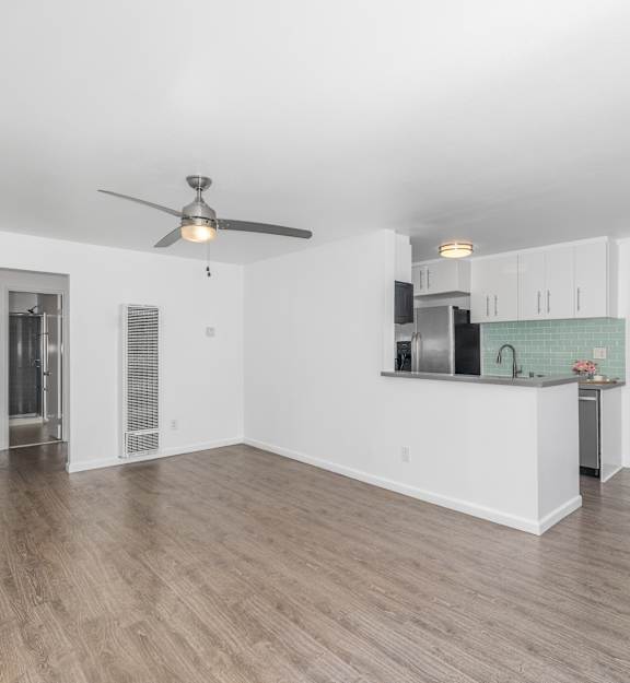 A spacious living room with a ceiling fan and hardwood flooring.