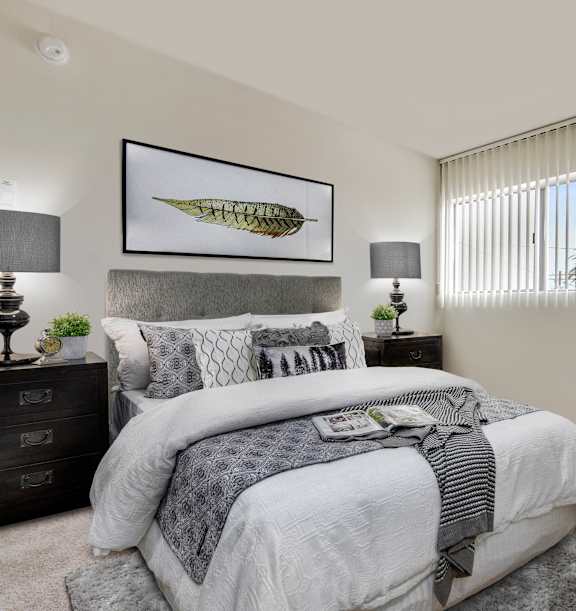 A bedroom with a large bed and two lamps on either side of a nightstand.