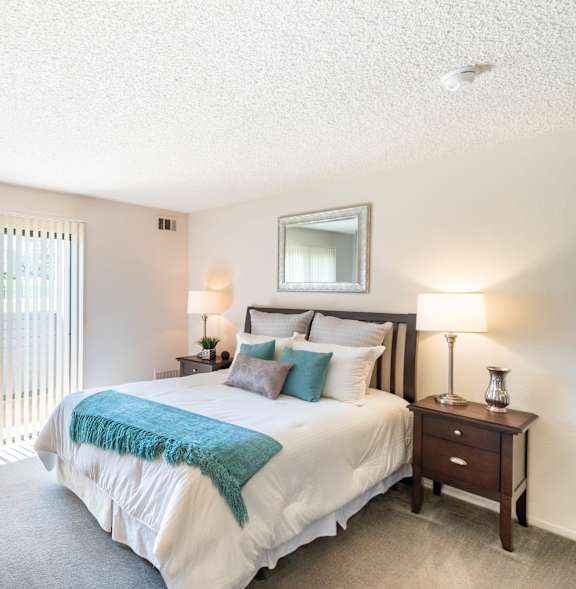 A bedroom with a large bed and a potted plant at Chaparral Apartments , California 93551
