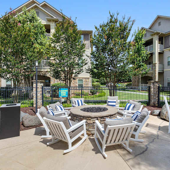 A patio with chairs and a table surrounded by trees and apartment buildings.