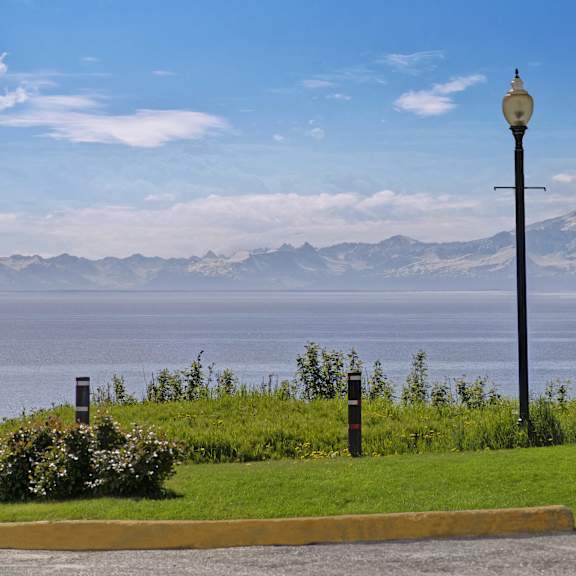 A view of the ocean and mountains from grassy area with a lamp post at Bay Arms Apartments.