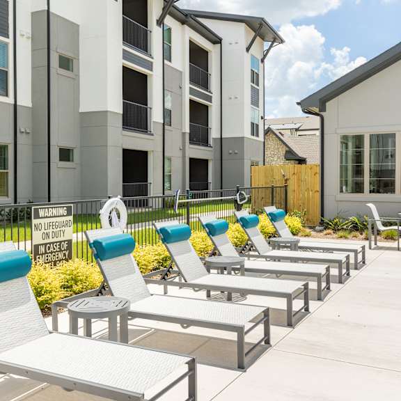 A wooden bench sits in front of a grassy hill.at 901 Rendon, Texas
