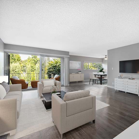 A modern living room with a flat screen TV and a kitchen area in the background.