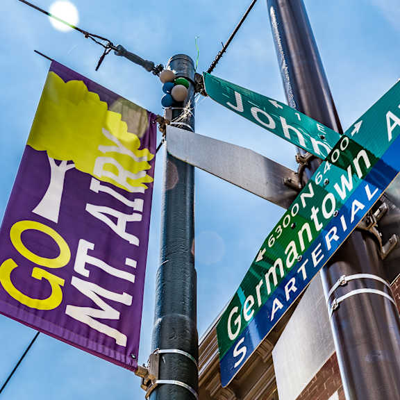 A street sign pole with a sign for Germantown and a banner that says Go Mt. Airy.