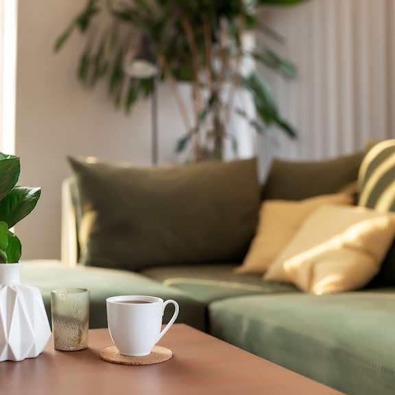A table with a cup of coffee, a plant, a book, and a vase.