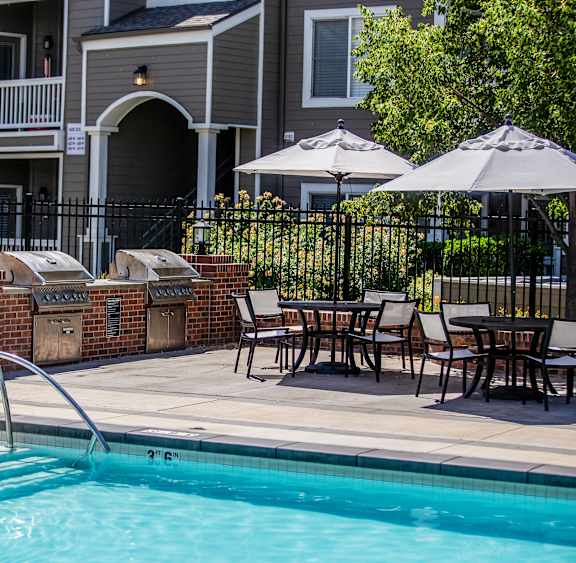 A pool with a slide and a table with chairs in front of a building.