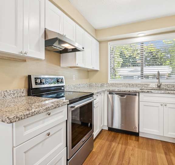 A kitchen with white cabinets and granite countertops.