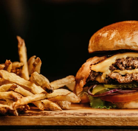 people sitting around a table eating food with burgers and fries