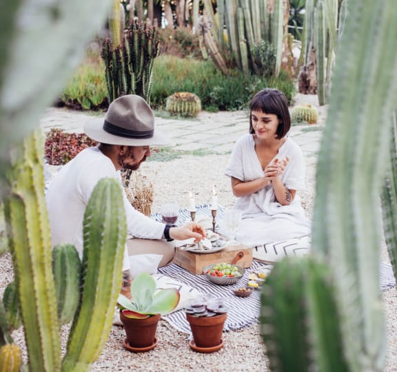 A man and woman are sitting at a table surrounded by cacti at The Rey Downtown, Phoenix, 85003