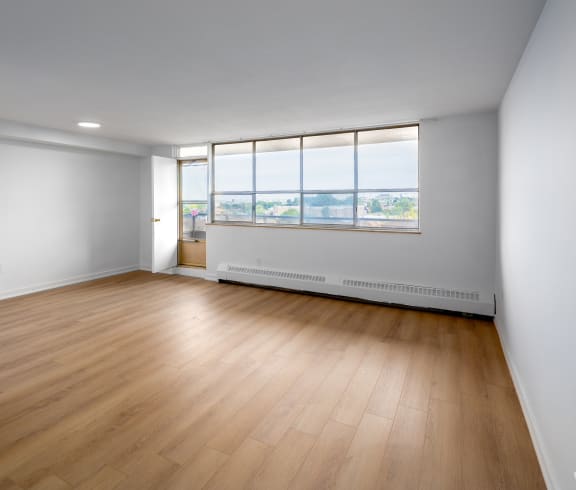 an empty living room with wood floors and a window