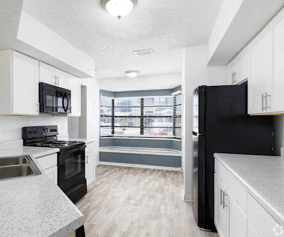 an empty kitchen with black appliances and white cabinets