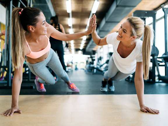 Two women high-fiving each other in a gym.