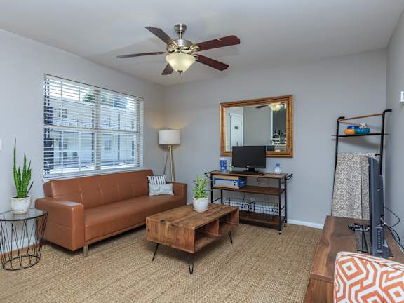 a living room with a ceiling fan and a large window
