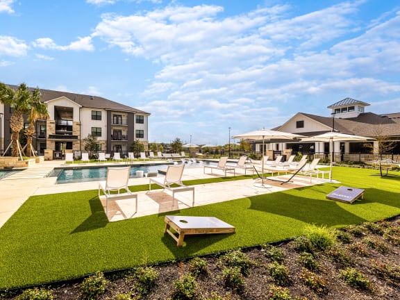 a pool and lounge chairs in a yard with apartments in the background
