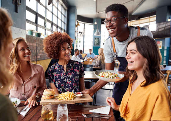 a group of people sitting around a table eating food at a restaurant