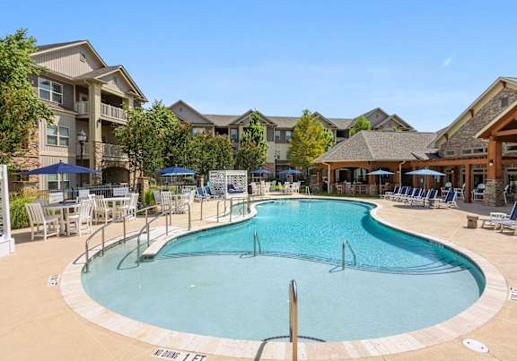 A large outdoor swimming pool surrounded by lounge chairs and umbrellas.