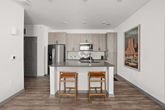 A kitchen with a bar stool and a fridge. at The Maddox Luxury Apartment Homes, Buckeye, AZ, 85326