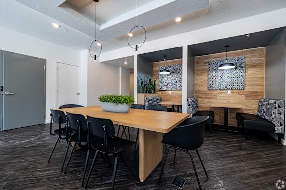 A modern dining room with a wooden table and black chairs.